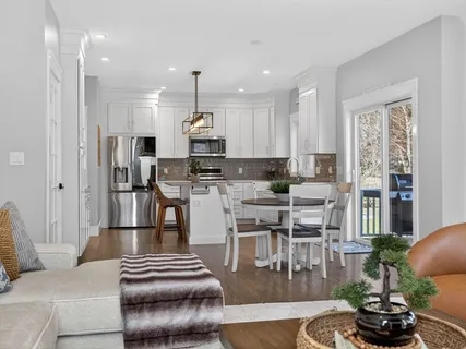 a kitchen with stainless steel appliances kitchen island granite countertop a refrigerator a stove a sink and a dining table with wooden floor