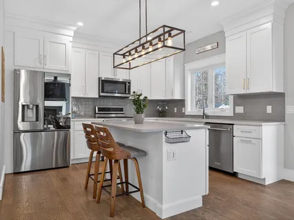 a kitchen with stainless steel appliances kitchen island granite countertop a stove top oven a sink a refrigerator with a dining table and chairs