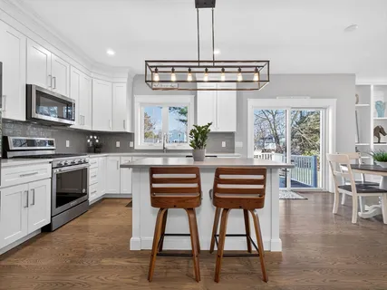 a kitchen with stainless steel appliances granite countertop a stove top oven a sink a dining table and chairs with wooden floor