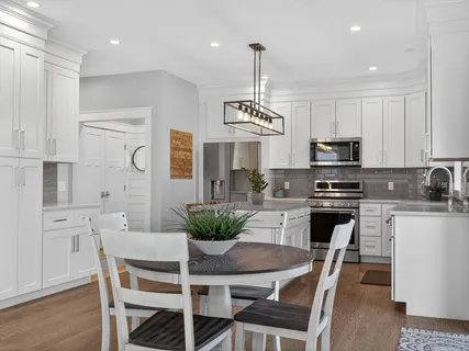 a kitchen with stainless steel appliances kitchen island granite countertop a dining table chairs and white cabinets