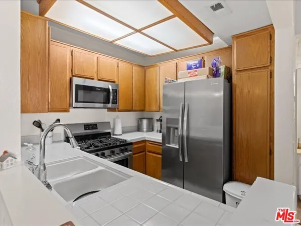 a kitchen with stainless steel appliances granite countertop a refrigerator a stove top oven a sink and dishwasher
