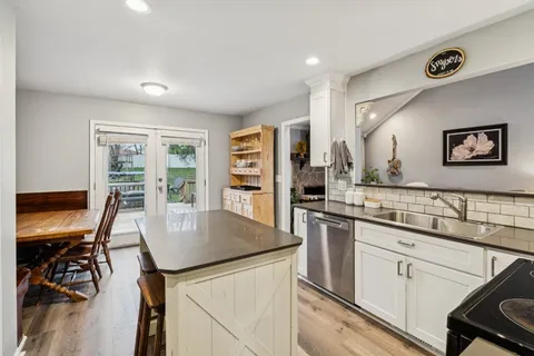 a kitchen with stainless steel appliances granite countertop a stove a refrigerator a sink a dining table and chairs with wooden floor