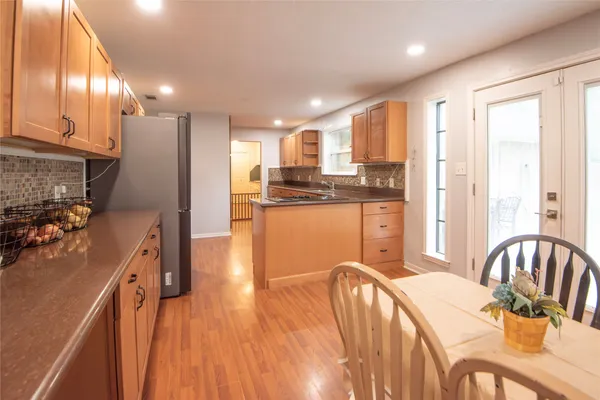 a kitchen with stainless steel appliances granite countertop a refrigerator a stove top oven a sink dishwasher and wooden cabinets with wooden floor
