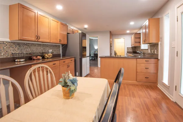 a kitchen with stainless steel appliances granite countertop a refrigerator a stove top oven a sink dishwasher and white cabinets with wooden floor