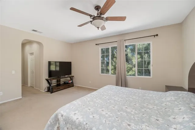 a bedroom with a bed and a flat tv screen on the dresser