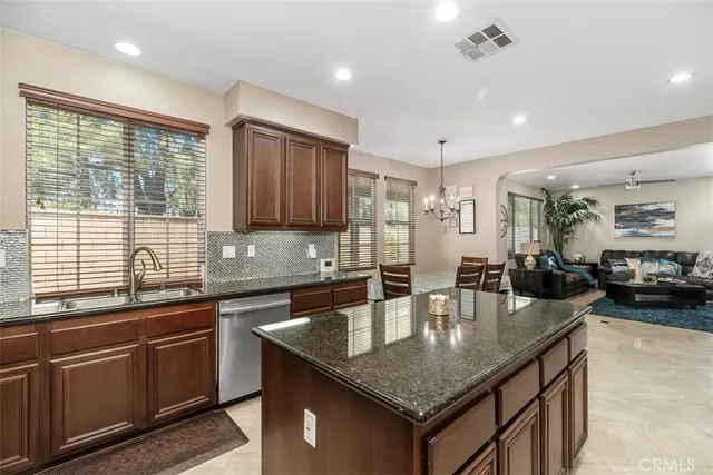 a kitchen with stainless steel appliances granite countertop a sink a center island and couches