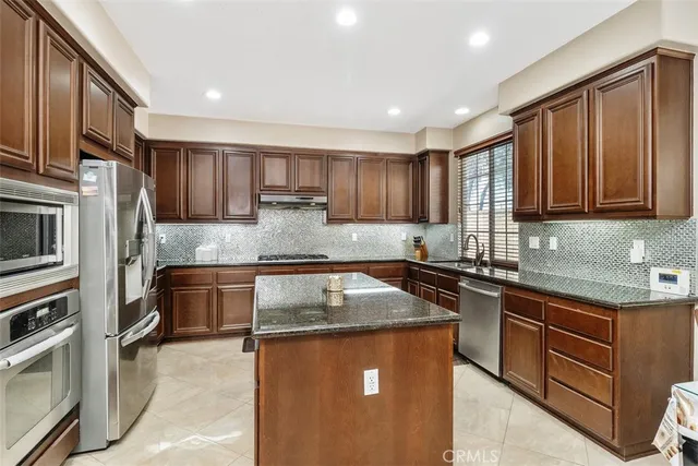 a kitchen with stainless steel appliances granite countertop a sink stove microwave and refrigerator