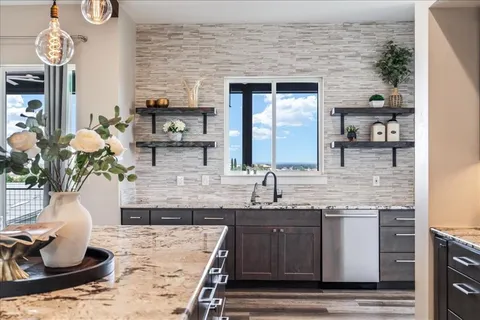 a kitchen with granite countertop a sink a stove and cabinets