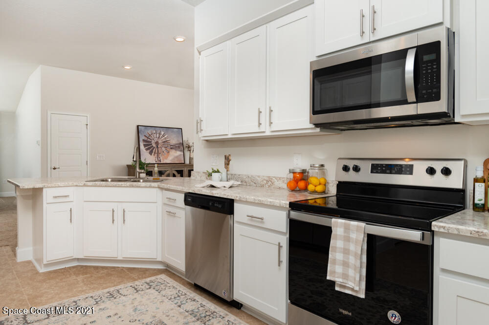 991 Tupelo Circle Cocoa, FL 32926 - Photo 6 of 23 a kitchen with stainless steel appliances granite countertop a stove a microwave and white cabinets