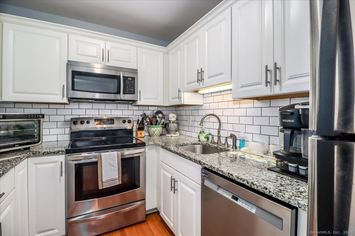 107 Hidden Knolls Circle, Unit 107 Monroe, CT 06468 - Photo 3 of 31 a kitchen with granite countertop a sink stove and microwave