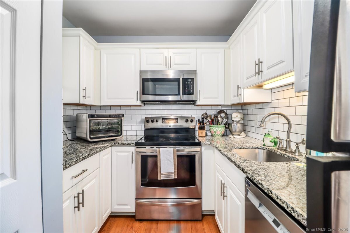 107 Hidden Knolls Circle, Unit 107 Monroe, CT 06468 - Photo 4 of 31 a kitchen with granite countertop a sink stove and microwave