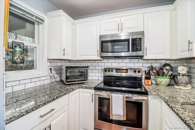a kitchen with granite countertop a stove top oven microwave and cabinets