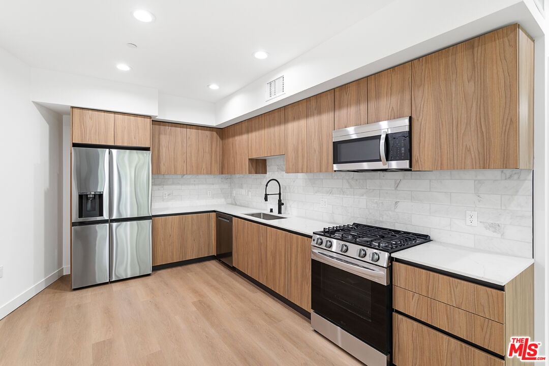 a kitchen with stainless steel appliances a refrigerator sink and microwave