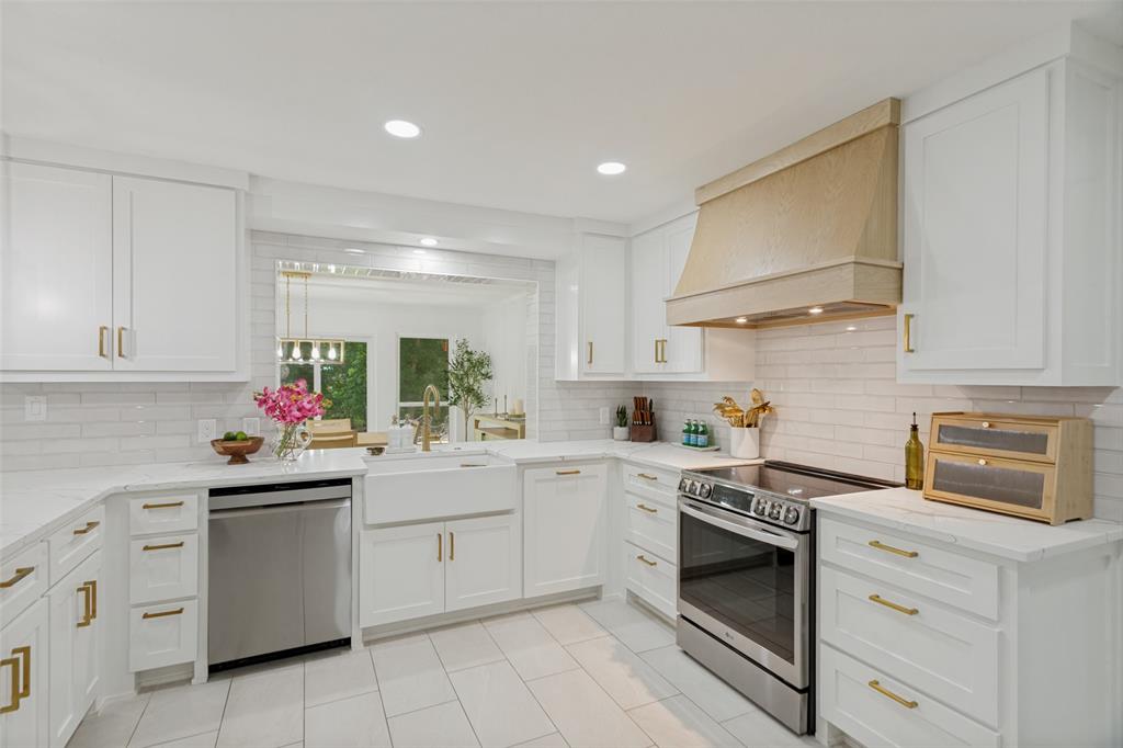 4316 Springbranch Drive Benbrook, TX 76116 - Photo 19 of 39 Bright kitchen featuring white shaker cabinetry with gold-finish hardware, a wood-finish range hood, stainless steel appliances, and white subway tile backsplash