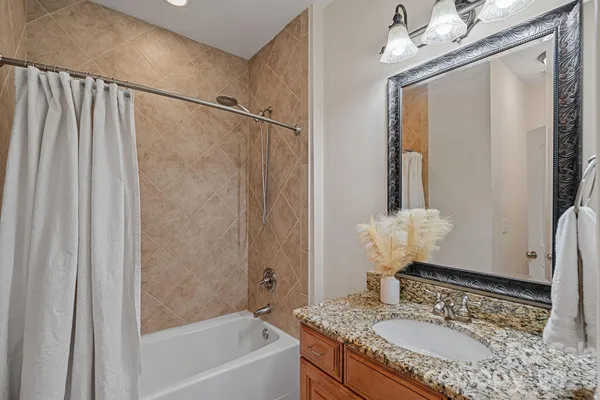 a bathroom with a granite countertop sink a mirror and a bathtub