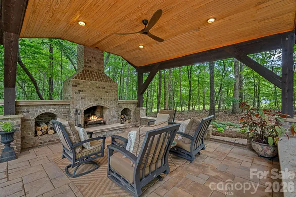 a view of a patio with a table and chairs under an umbrella with a fireplace