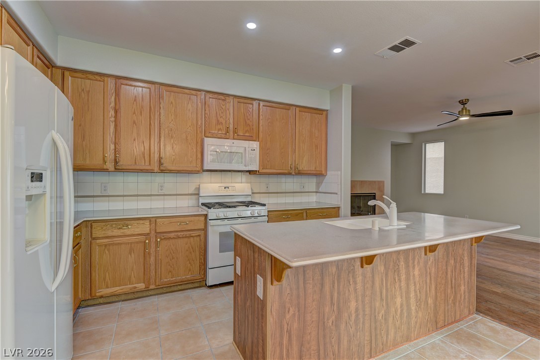 1813 Snow Spring Lane Las Vegas, NV 89134 - Photo 13 of 37 A functional kitchen with natural wood cabinetry and a central island overlooking the living space.
