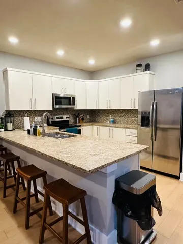 a kitchen with stainless steel appliances granite countertop a table chairs sink refrigerator and microwave