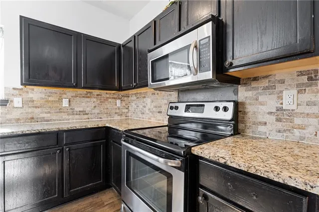 a kitchen with granite countertop cabinets stainless steel appliances and wooden floor