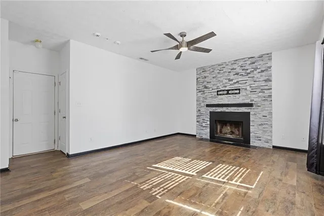 a view of a livingroom with a fireplace a ceiling fan and wooden floor