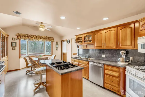 a kitchen with stainless steel appliances granite countertop a stove top oven a sink dishwasher and white cabinets with wooden floor