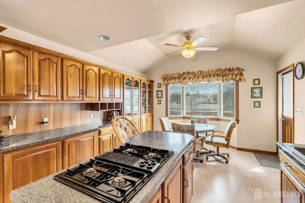 a kitchen with stainless steel appliances granite countertop a stove a refrigerator a sink dishwasher a dining table and chairs with wooden floor