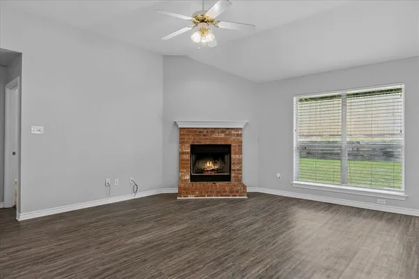 an empty room with wooden floor chandelier fan and windows
