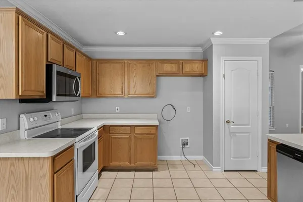 a kitchen with a sink dishwasher a stove and white cabinets with wooden floor