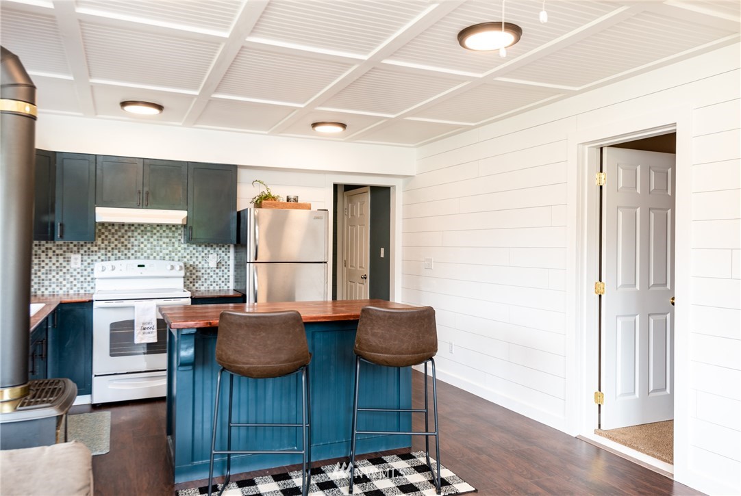 6565 Old Guide Road Bellingham, WA 98226 - Photo 22 of 27 a kitchen with stainless steel appliances kitchen island granite countertop a table chairs in it and wooden floors