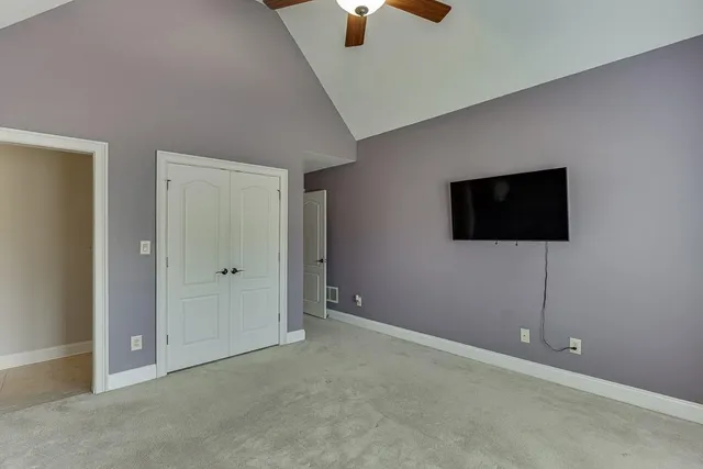 a spacious bedroom with a large bed a chandelier and closet