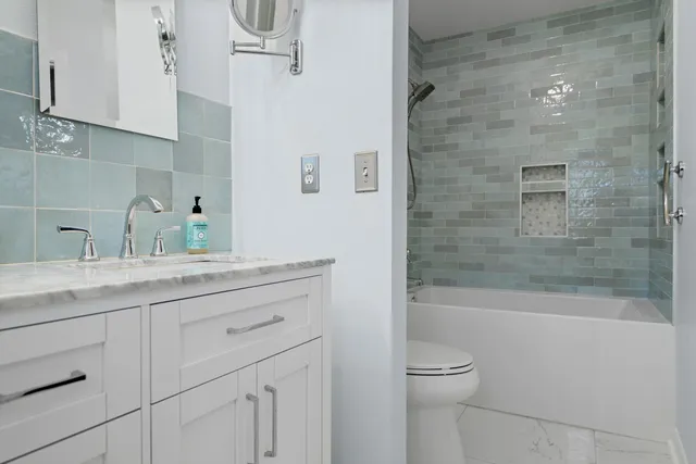 a bathroom with a granite countertop sink a toilet and shower
