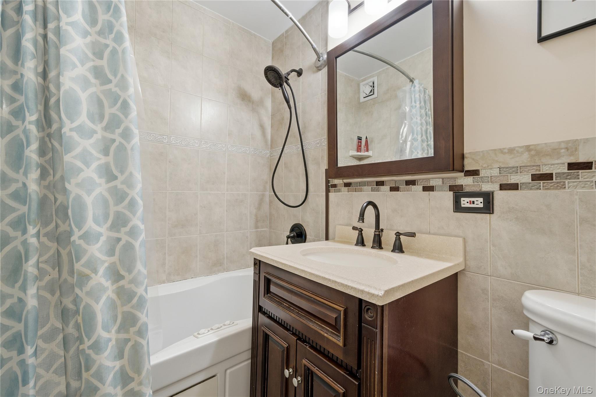 420 Shore Road, Unit 3M Long Beach, NY 11561 - Photo 7 of 23 Bathroom with vanity, shower / tub combo with curtain, and tile walls