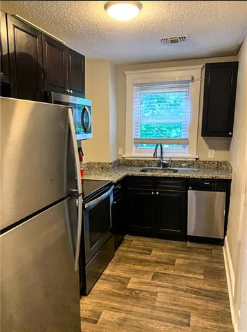 a kitchen with granite countertop a refrigerator a sink and a stove