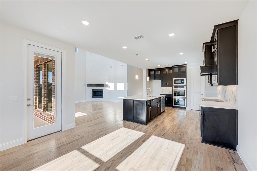 5622 Rowlan Row Midlothian, TX 76065 - Photo 13 of 35 a large living room with stainless steel appliances kitchen island granite countertop a refrigerator stove oven with wooden floor