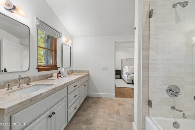 a spacious bathroom with a granite countertop sink a mirror and shower