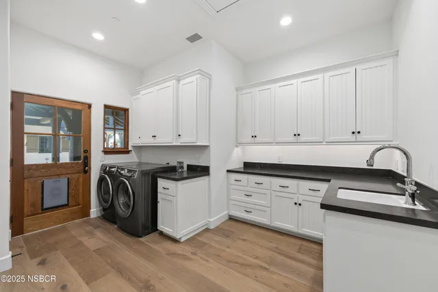 a kitchen with granite countertop a stove top oven a sink dishwasher and white cabinets with wooden floor