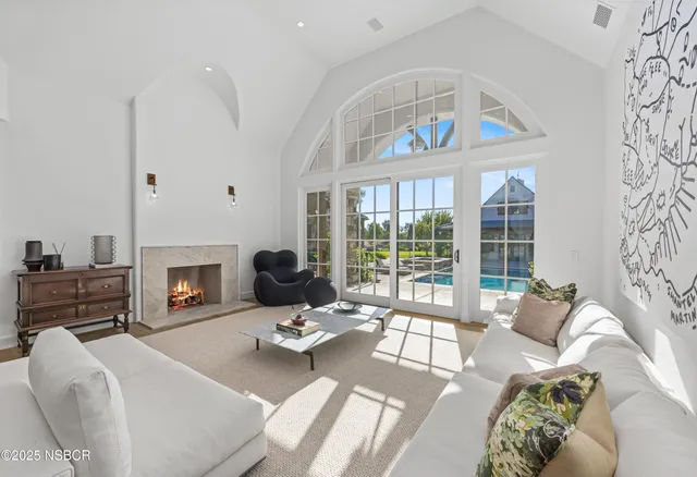 a living room with furniture a fireplace and a floor to ceiling window