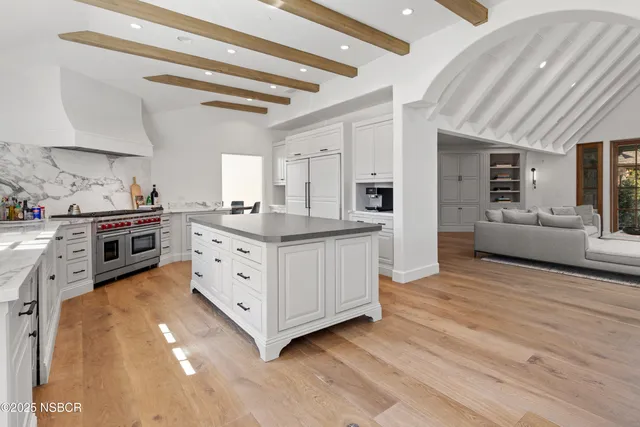 a kitchen with stainless steel appliances a sink and wooden floor
