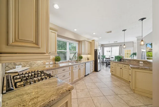 a large white kitchen with granite countertop a lot of counter space and stainless steel appliances