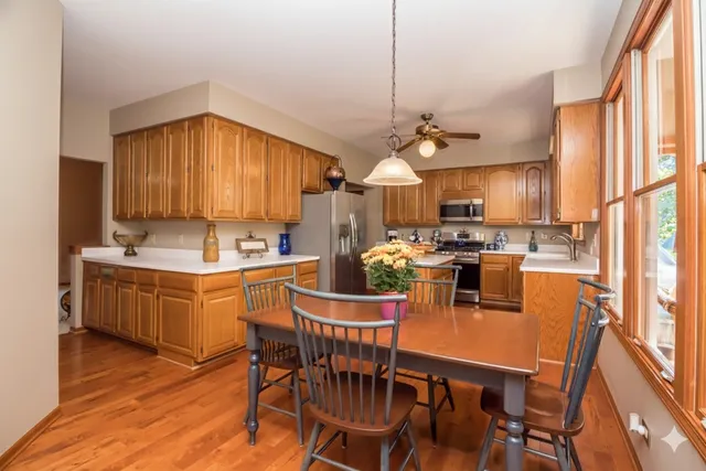 a kitchen with stainless steel appliances granite countertop a sink dishwasher a stove a refrigerator with a dining table and chairs with wooden floor