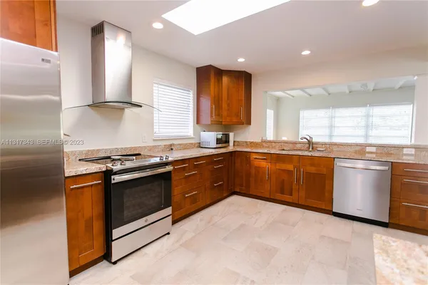 a kitchen with stainless steel appliances granite countertop a stove a sink and a microwave