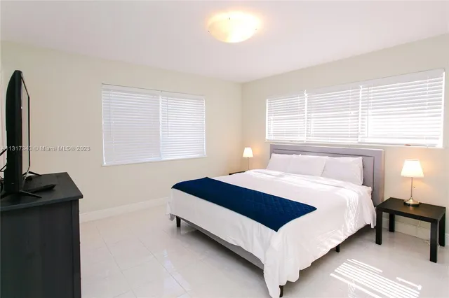 a bedroom with a bed and a flat tv screen on a dresser