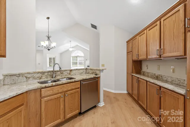 a kitchen with kitchen island granite countertop a sink and dishwasher with wooden floor