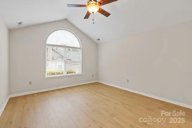 a view of a room with wooden floor and ceiling fan
