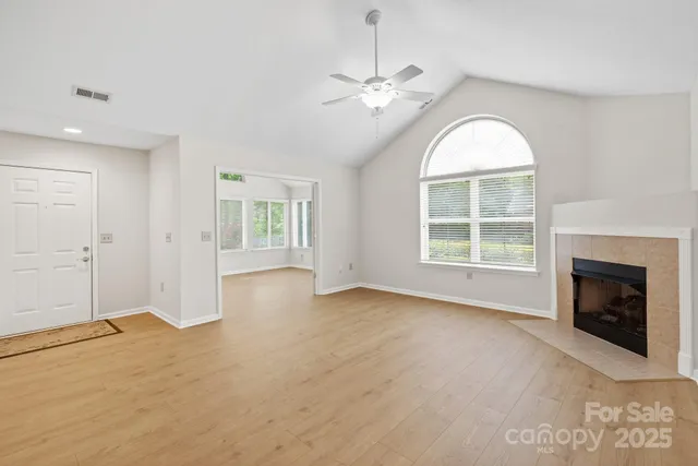 an empty room with windows and fireplace