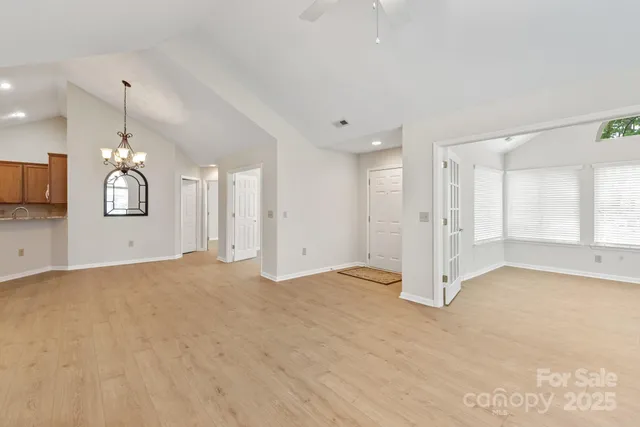 a view of an empty room with window and wooden floor