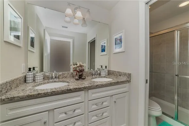 a bathroom with a granite countertop sink a toilet and a mirror