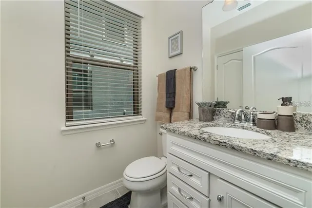 a bathroom with a granite countertop sink toilet and mirror