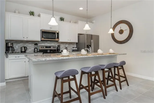 a kitchen with stainless steel appliances a white table chairs and a refrigerator