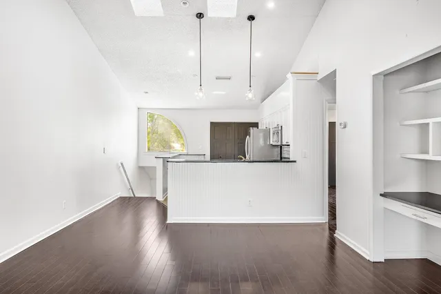 an empty room with wooden floor fan and windows
